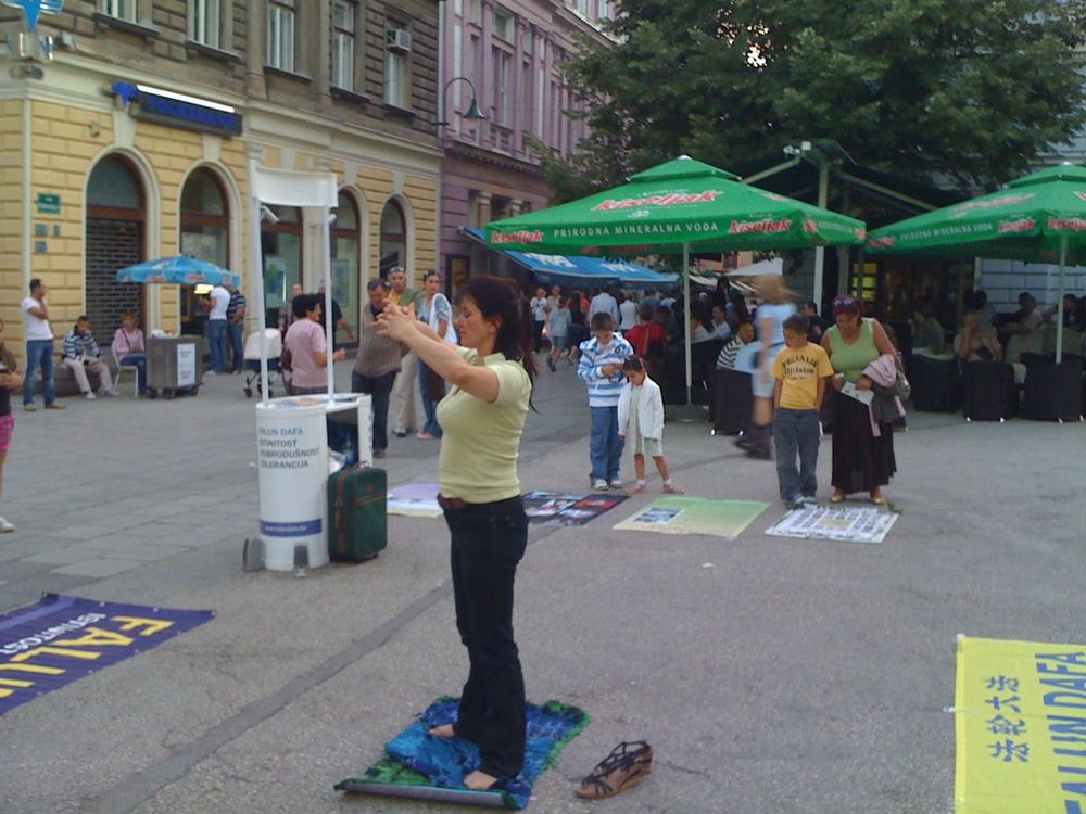 Praktikantica Falun Gonga radi vježbe, dok prolaznici pažljivo čitaju informacije o progonu.
