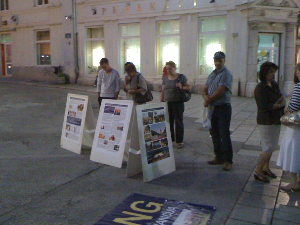 Prolaznici posmatraju plakate o Falun Gongu i progonu u Kini.