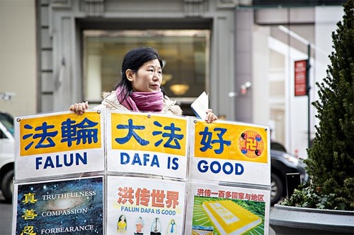 Wang Huijuan, ispred zgrade Empire State Building u Manhattanu u Njujorku, 12. januara 2017, drži u rukama plakat kako bi pomogla kineskim turistima da shvate činjenice o progonu Falun Gonga u Kini. (Samira Bouaou / Epoch Times)